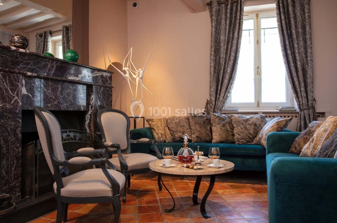 Salon élégant avec cheminée en marbre, fauteuils classiques, canapé bleu, table basse et décoration raffinée.