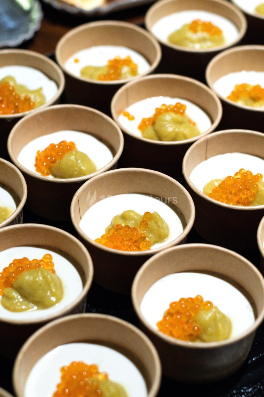Petits pots en carton contenant une mousse blanche garnie de perles orange et d'une purée verte.