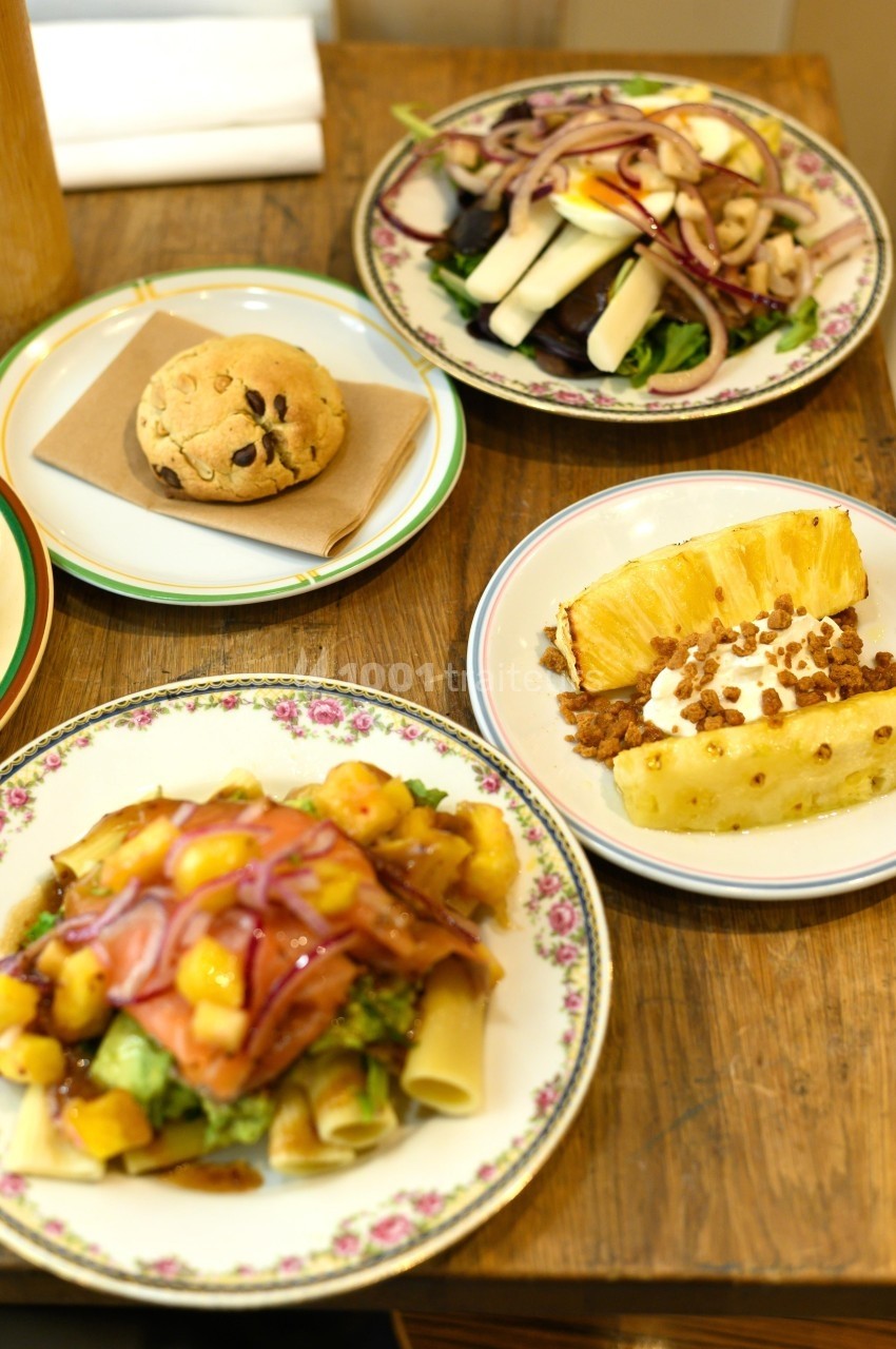 Assiette de pâtes aux légumes, salade, dessert à l'ananas et cookie, disposés sur une table en bois.