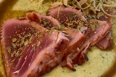 Assiette de magret de canard tranché sur purée de patates douces, garnie de persil et accompagnée d'une sauce.