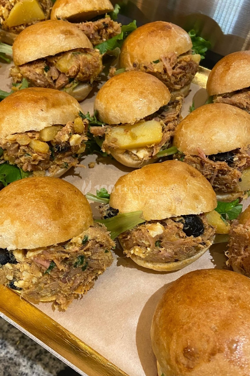 Petits sandwichs briochés garnis de viande effilochée, légumes et olives, présentés sur un plateau en bois.