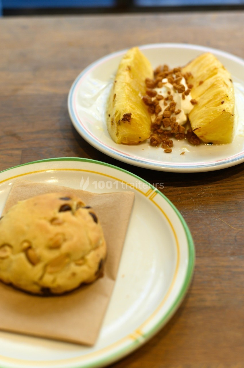 Assiette avec des tranches d'ananas, crème et granola, et une autre avec un cookie aux pépites de chocolat.