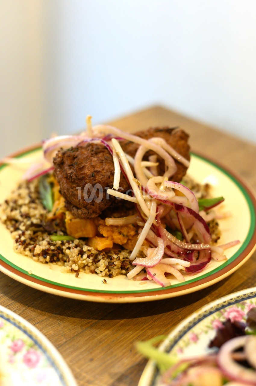 Assiette de quinoa garnie de légumes rôtis, falafel et oignons rouges marinés.
