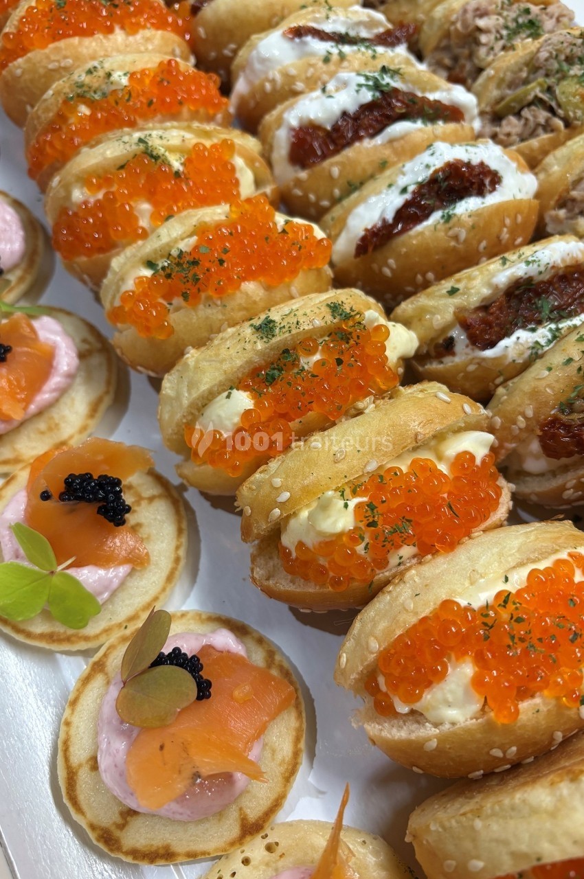 Assortiment de bouchées apéritives avec blinis au saumon et mini-sandwichs garnis d'œufs de poisson et de crème.