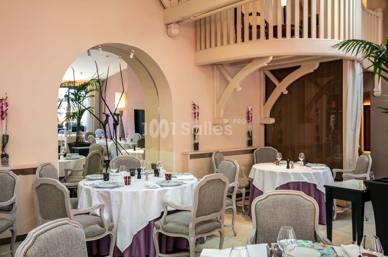 Salle de restaurant élégante avec tables dressées, chaises capitonnées et décor raffiné dans un cadre lumineux.