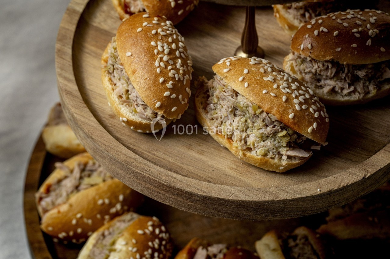 Petits pains garnis de rillettes disposés sur un présentoir en bois à deux niveaux.
