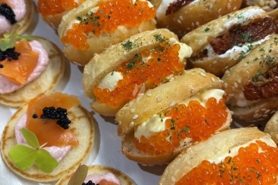 Assortiment de bouchées apéritives avec blinis au saumon et caviar, et mini-sandwichs garnis de crème et œufs de poisson.