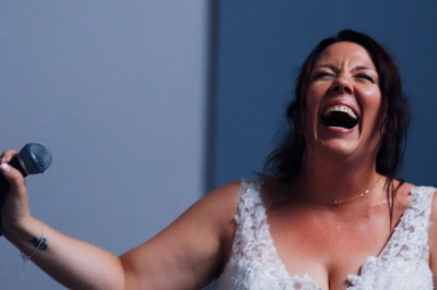 Femme assise dans une lumière tamisée, entourée de verres, regardant vers l'objectif.