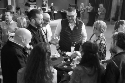 Femme assise dans une lumière tamisée, entourée de verres, regardant vers l'objectif.