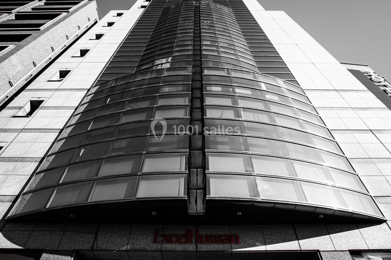 Façade moderne d'un immeuble en verre et acier, vue en contre-plongée sous un ciel dégagé.