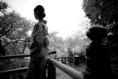 Femme assise dans une lumière tamisée, entourée de verres, regardant vers l'objectif.