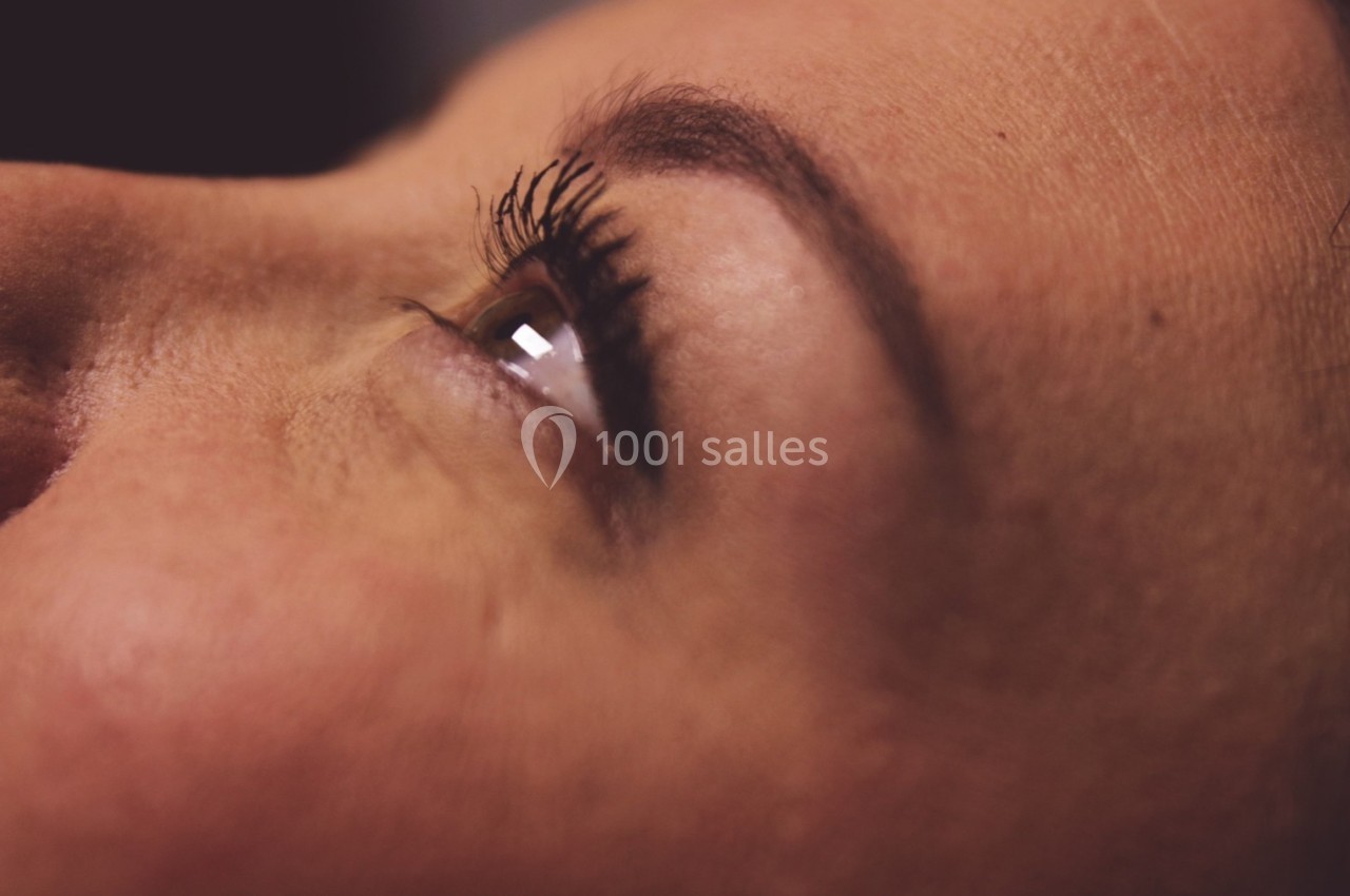 Gros plan sur le visage d'une femme, mettant en avant son œil regardant vers le haut et ses cils.