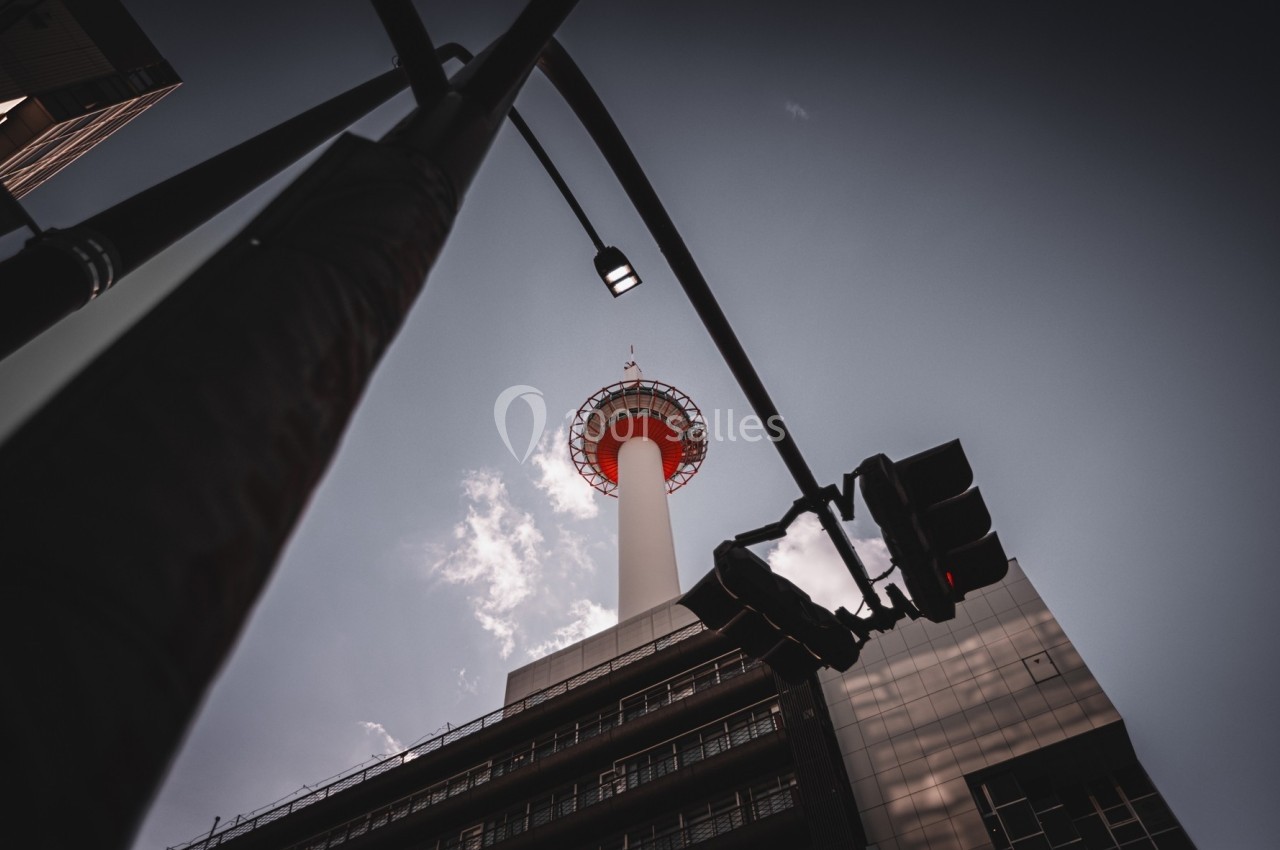 Vue en contre-plongée d'une tour blanche et rouge sous un ciel partiellement nuageux, avec des feux de circulation au…