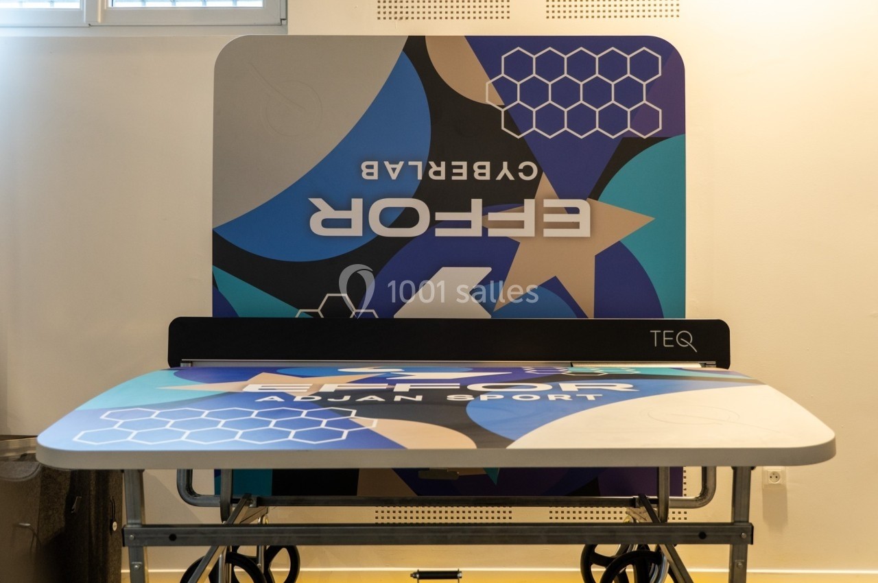 Table de sport design avec motifs géométriques bleus et noirs, installée dans une salle lumineuse.