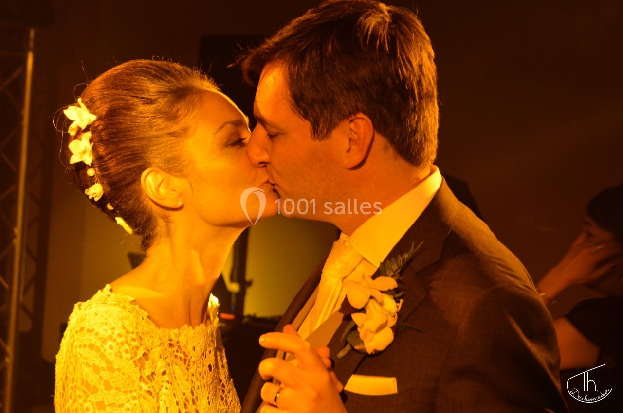 Un couple s'embrasse tendrement lors d'une cérémonie, éclairé par une lumière chaude et tamisée.