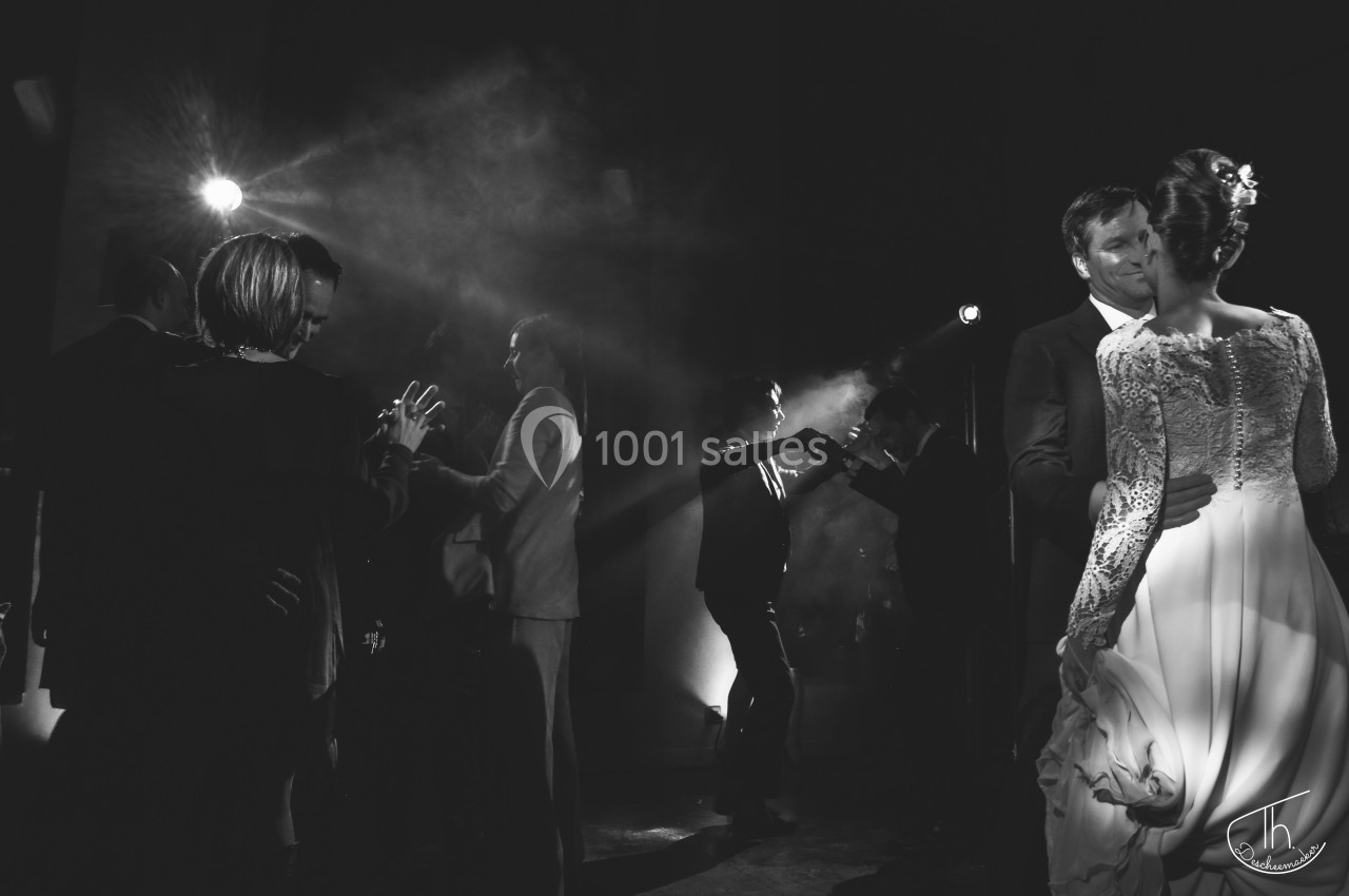 Des couples dansent dans une ambiance tamisée, éclairée par des projecteurs, lors d'un événement festif.