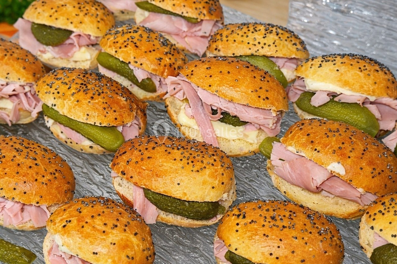 Petits pains garnis de jambon, cornichons et beurre, disposés sur une surface transparente.