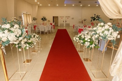 Décor de mariage avec canapé blanc, table assortie et fleurs blanches et vertes sur une estrade ornée.