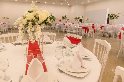 Décor de mariage avec canapé blanc, table assortie et fleurs blanches et vertes sur une estrade ornée.