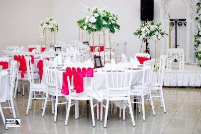 Décor de mariage avec canapé blanc, table assortie et fleurs blanches et vertes sur une estrade ornée.