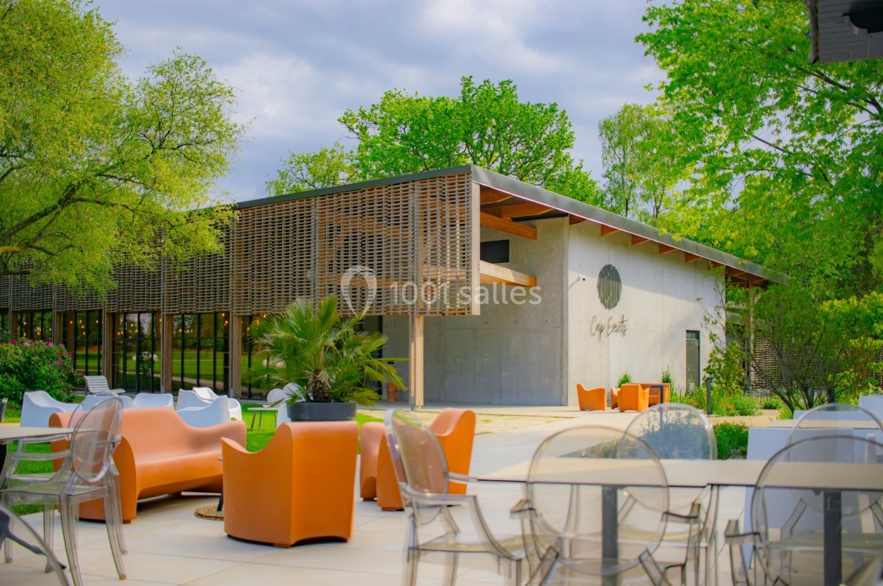 Terrasse aménagée avec mobilier coloré devant un bâtiment moderne entouré de verdure.