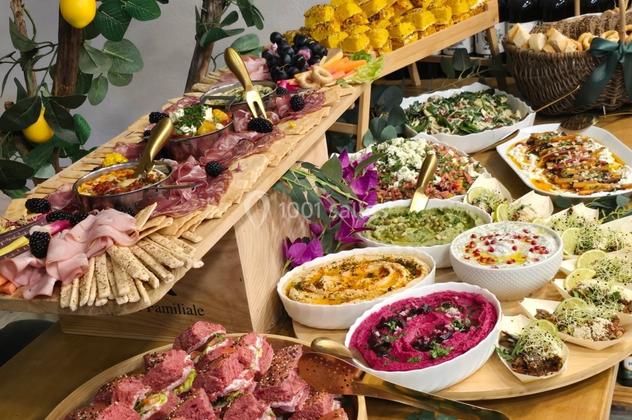 Buffet coloré avec plats variés : tartinades, salades, charcuteries, pains et décorations végétales.