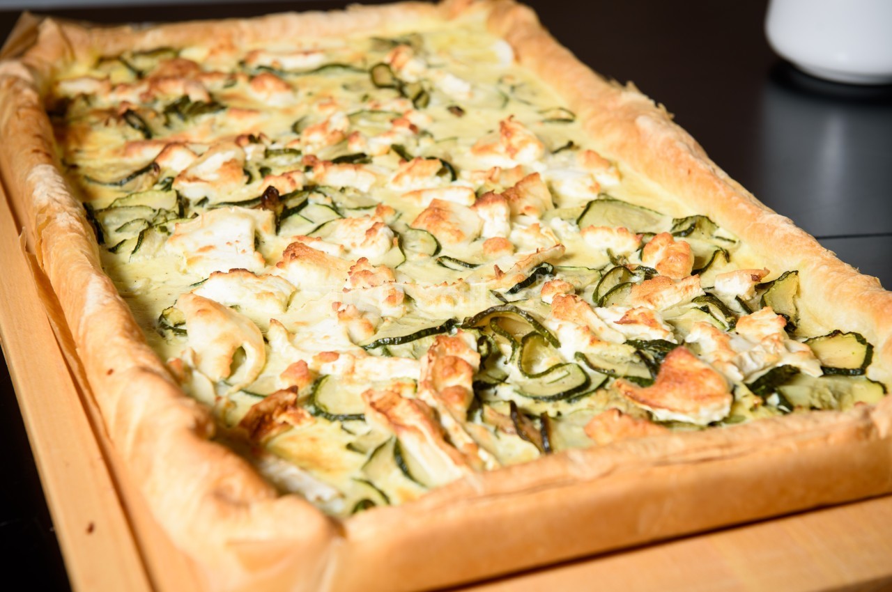 Tarte salée maison garnie de courgettes, fromage de chèvre et pâte feuilletée dorée.