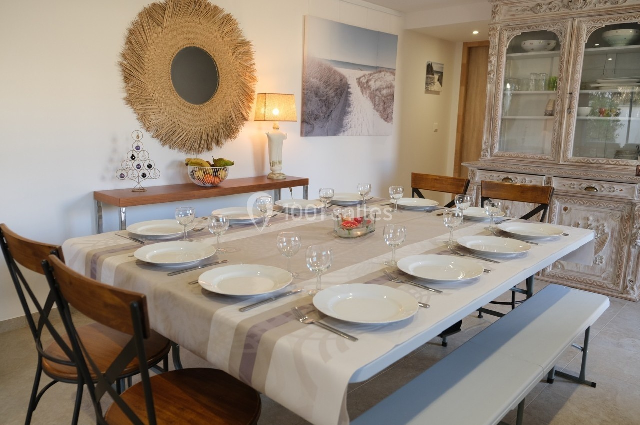 Table dressée pour un repas, avec assiettes, verres et couverts, dans une salle à manger décorée de façon chaleureuse.