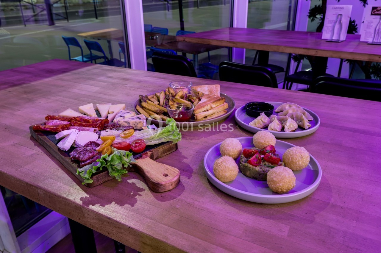 Plateau de charcuterie et fromages, frites, raviolis et boulettes servis sur une table en bois dans un restaurant.