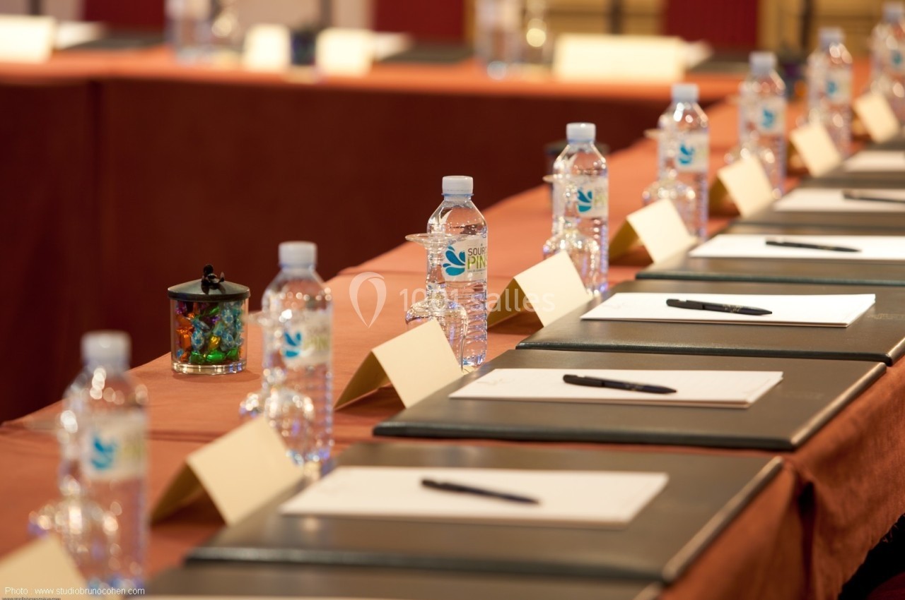 Bouteilles d'eau, carnets, stylos et porte-noms disposés sur une table de conférence.