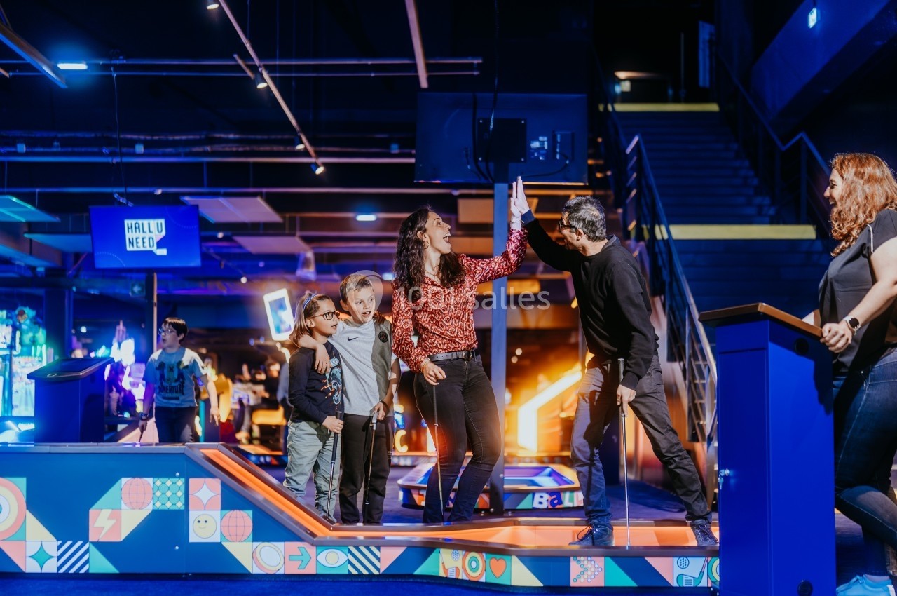 Des personnes jouent au mini-golf intérieur dans un espace lumineux et coloré, célébrant un coup réussi.