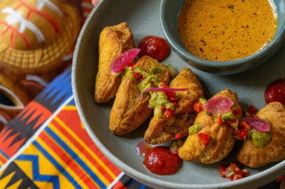 Miniature Traiteur Bordeaux (Gironde) - Okra #5 Cercle orné de motifs colorés entourant le mot ’OKRA’ sur un fond bleu foncé.