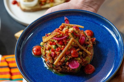 Miniature Traiteur Bordeaux (Gironde) - Okra #11 Cercle orné de motifs colorés entourant le mot ’OKRA’ sur un fond bleu foncé.