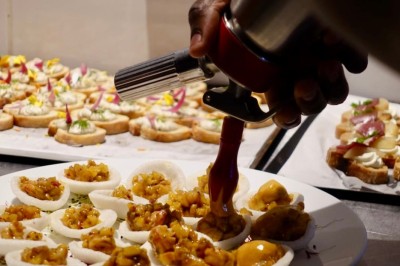 Miniature Traiteur Bordeaux (Gironde) - Okra #2 Cercle orné de motifs colorés entourant le mot ’OKRA’ sur un fond bleu foncé.