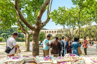 Un groupe de personnes explore une boîte ouverte au milieu de vignes ensoleillées.