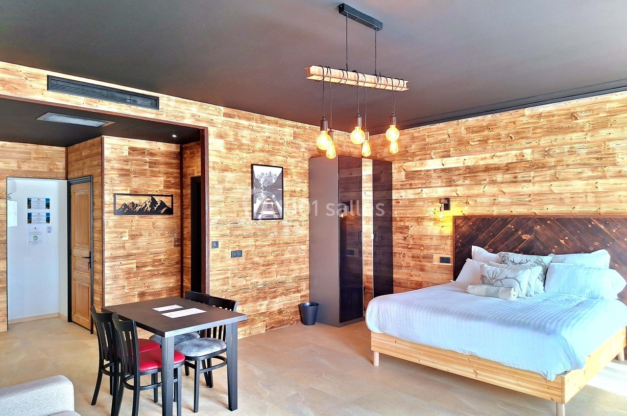 Chambre moderne avec murs en bois, lit double, table à manger et éclairage suspendu dans un style chaleureux.