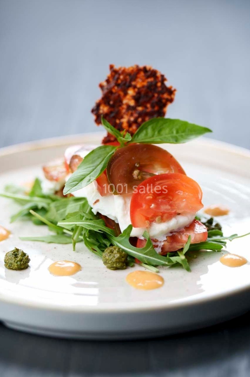 Assiette de salade composée de tomates, mozzarella, roquette, pesto, sauce et une tuile croustillante.