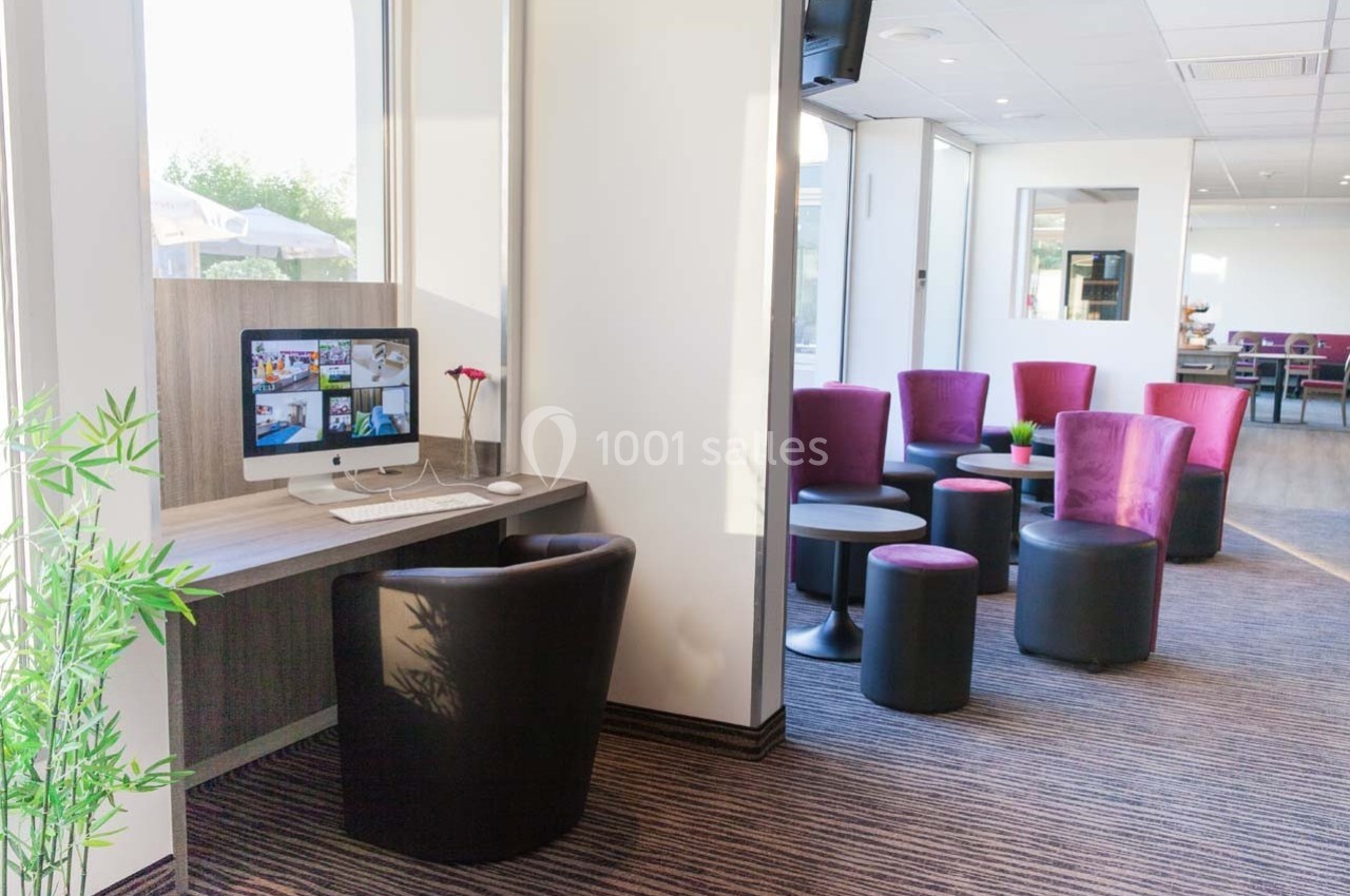 Espace détente avec fauteuils colorés et coin bureau équipé d'un ordinateur dans un intérieur lumineux.