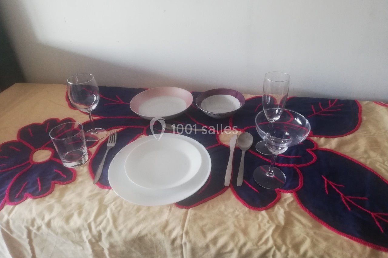 Table dressée avec une nappe colorée, deux couverts, assiettes, verres et bols disposés pour deux personnes.