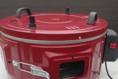 Four électrique portable rouge avec poignées noires, interrupteur latéral et ouverture pour ventilation.