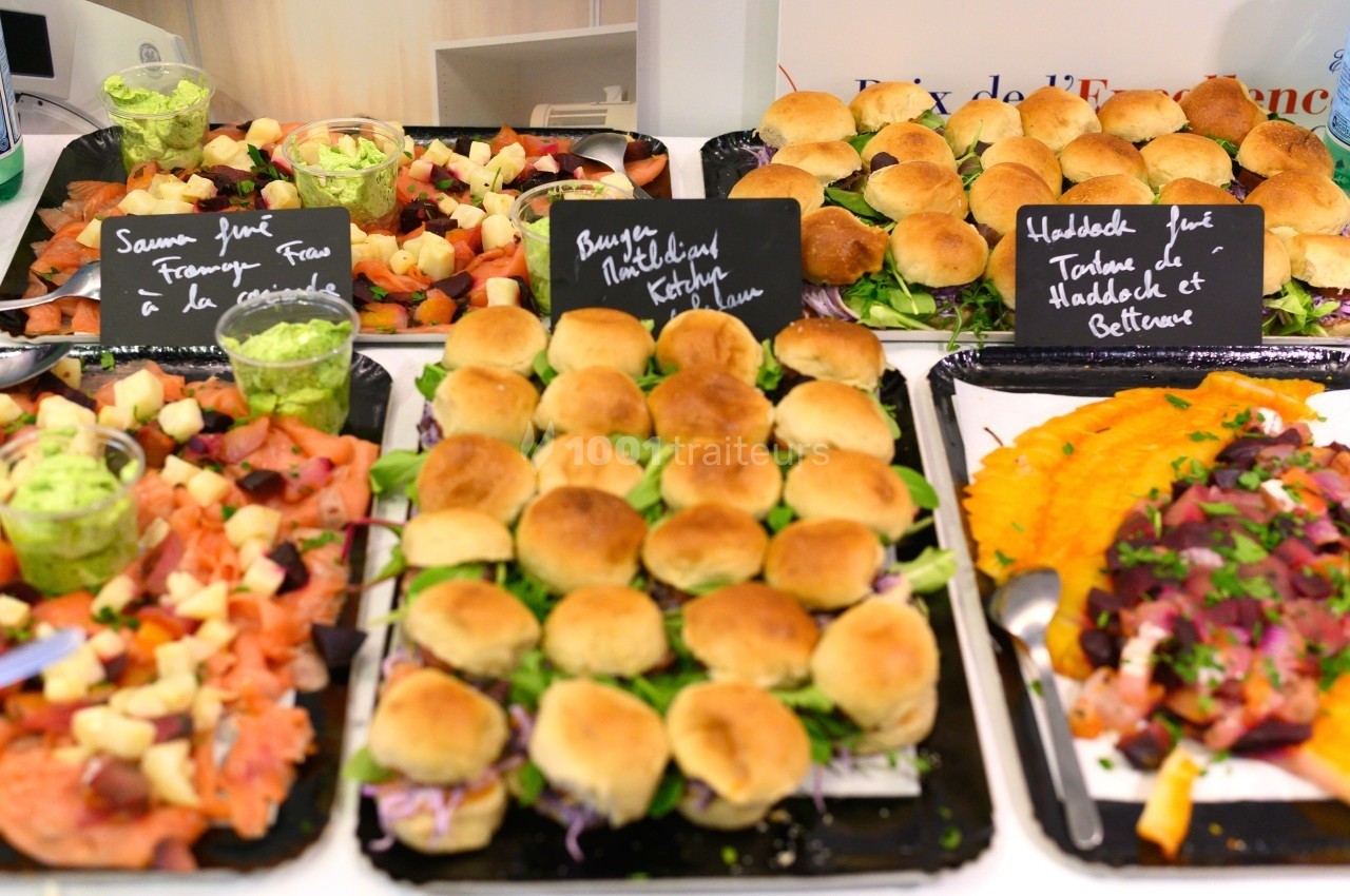 Plateaux de mini-burgers, toasts au saumon fumé et salade, accompagnés de sauces et garnitures variées.