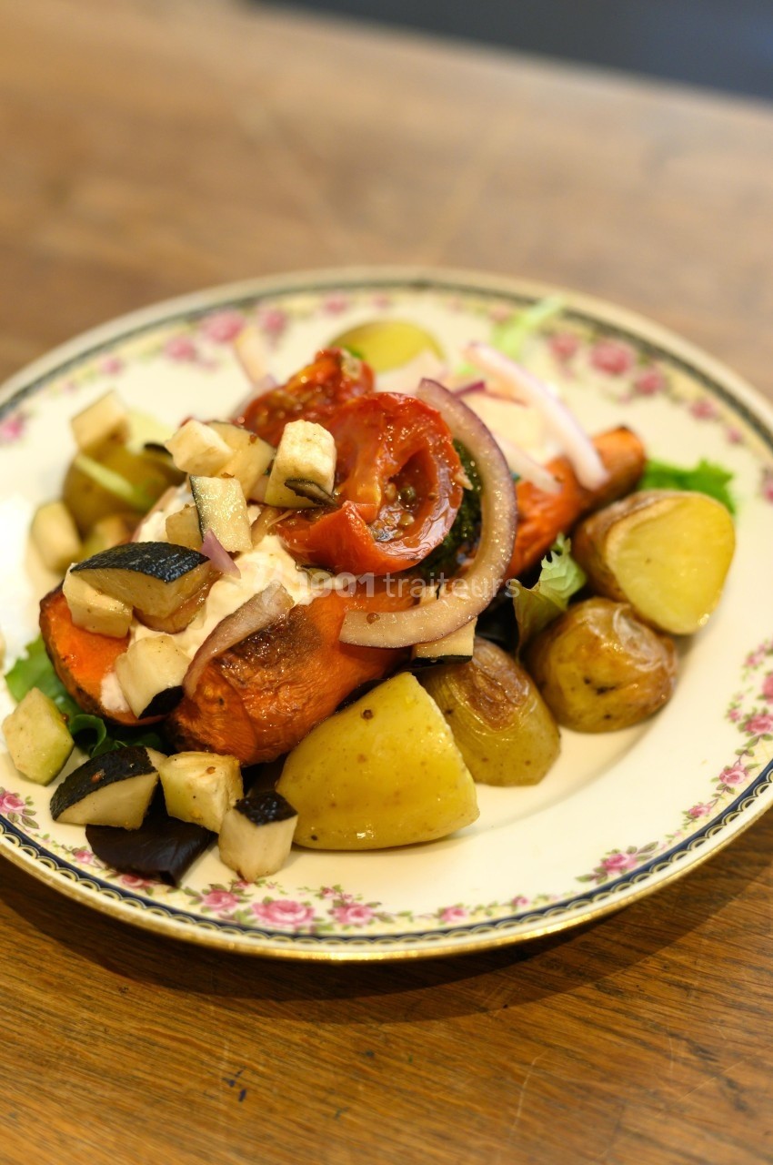 Assiette de légumes rôtis comprenant pommes de terre, carottes, aubergines, tomates et oignons, servie sur un plat décoré.