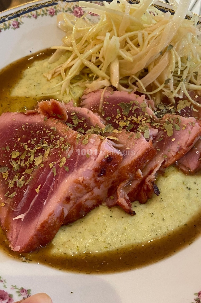 Tranches de thon mi-cuit servies sur une sauce verte, accompagnées de légumes croquants finement émincés.