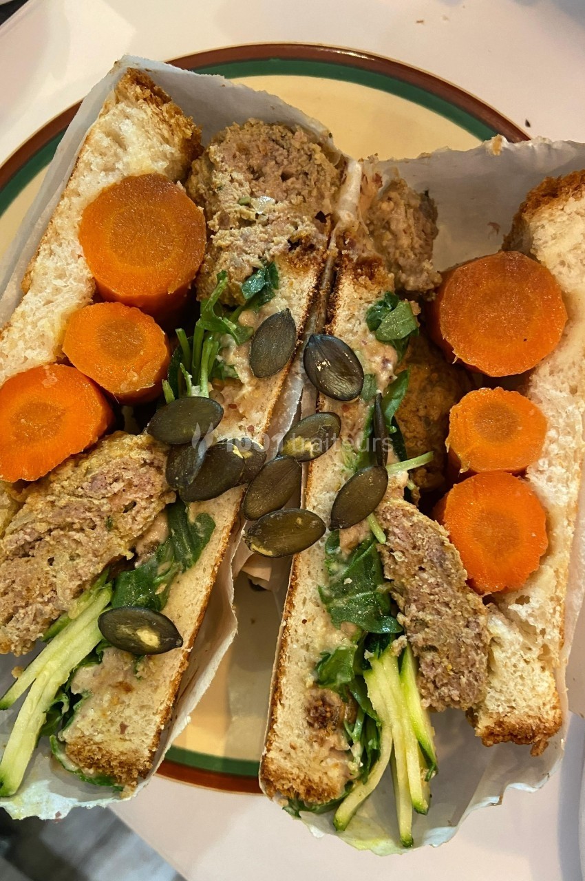 Sandwich ouvert garni de viande hachée, carottes en rondelles, courgettes râpées, roquette et graines de courge.