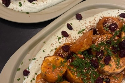 Assiette de magret de canard tranché sur purée de patates douces, garni de persil et accompagné d'une sauce.