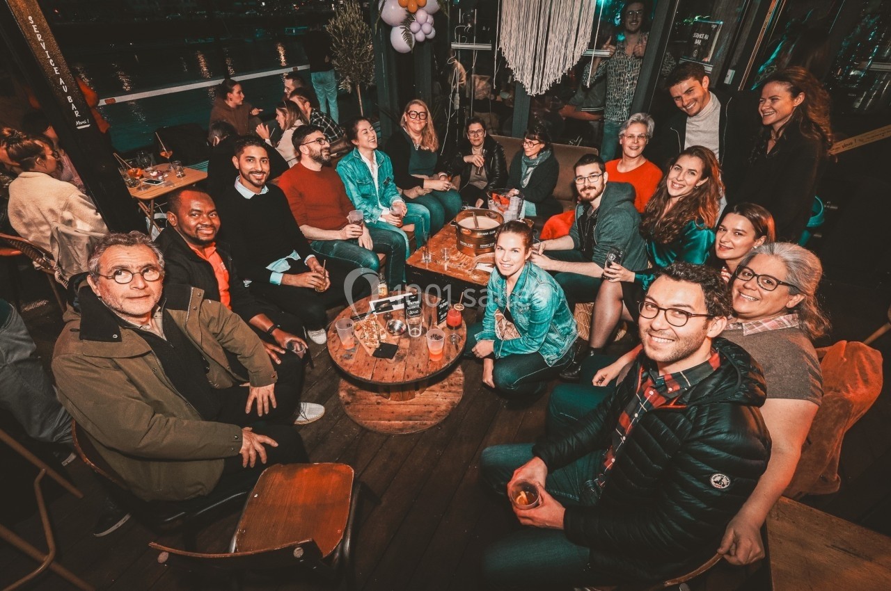 Groupe de personnes assises autour de tables dans un espace convivial, partageant un moment de détente en soirée.