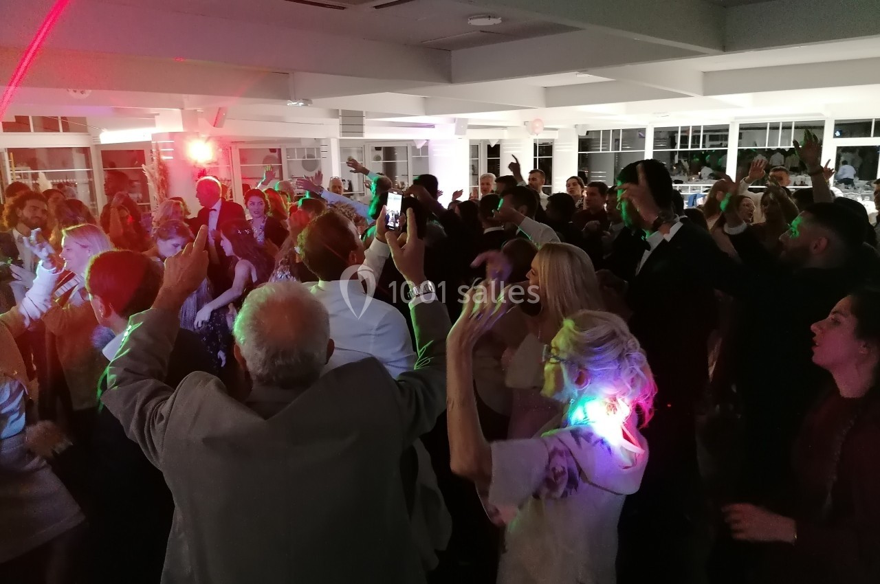 Groupe de personnes dansant dans une salle éclairée par des lumières colorées lors d'un événement festif.