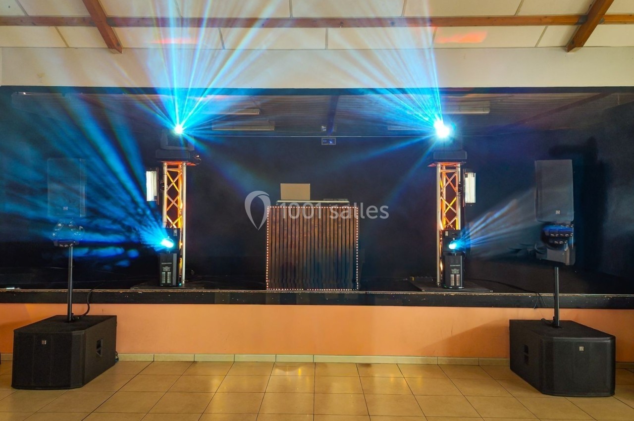 Scène équipée d'un matériel de sonorisation et d'éclairage avec projecteurs colorés et enceintes.