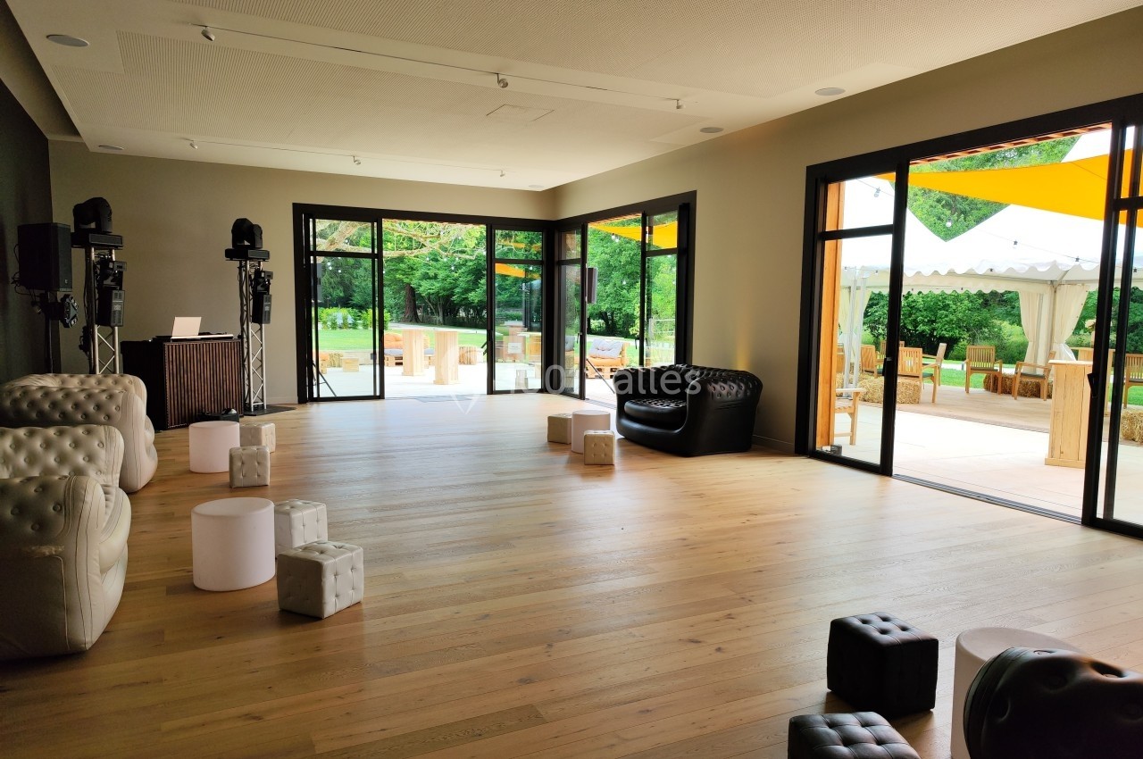 Salle lumineuse avec parquet, mobilier moderne et grandes baies vitrées donnant sur une terrasse et un jardin.