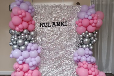 Arc décoratif en ballons roses, bleus et dorés avec papillons, installé dans une pièce au sol en bois.